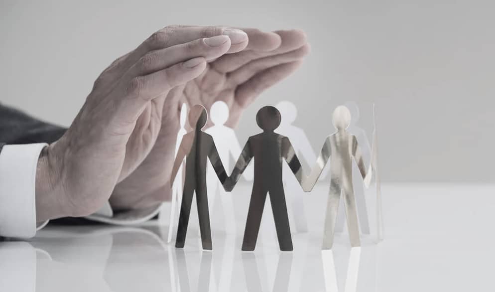 Hand som skyddar pappersfigurer – symboliserar HR och ledarskap med sunda gränser