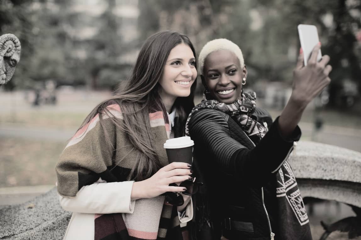 Två kvinnor ler och tar en selfie tillsammans – symboliserar om man kan sätta gränser med vänner.