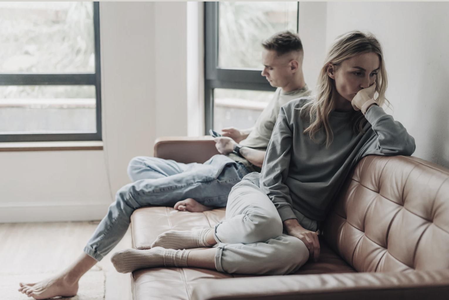 Två personer sitter tysta i soffan och undviker ögonkontakt – en bild som illustrerar konflikträdsla i vardagliga relationer.