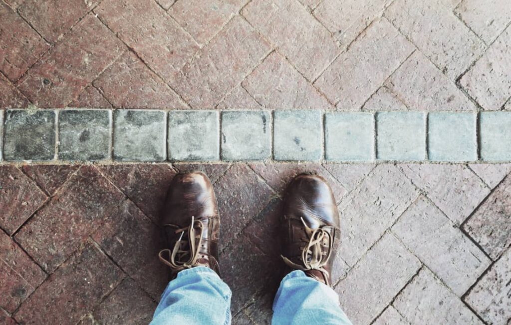 Ett par skor står framför en markerad linje på marken – symbol för personliga gränser och självrespekt.