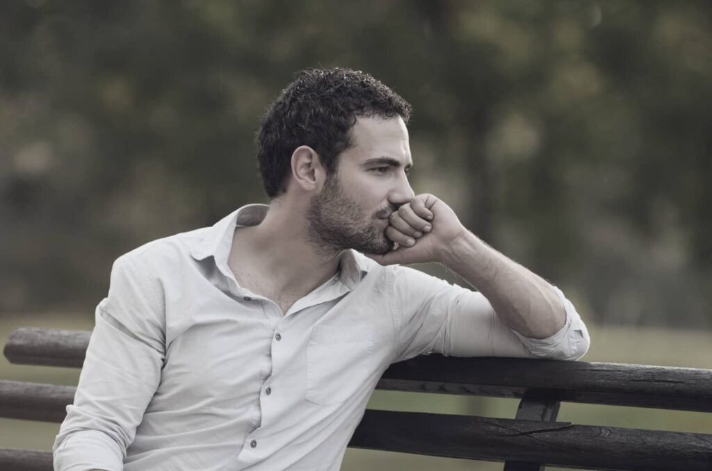 Person som sitter ensam och funderar, som symboliserar den inre oro som kan driva hjälpbeteenden.